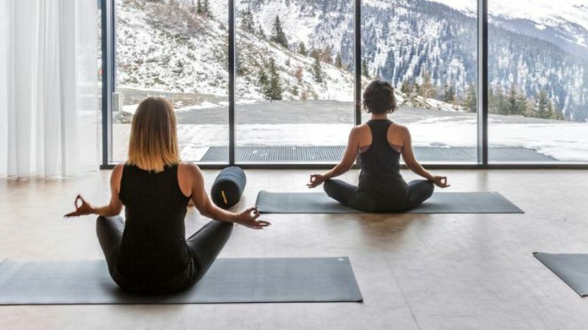 Turistas a praticarem yoga com vista para as montanhas cobertas de neve
