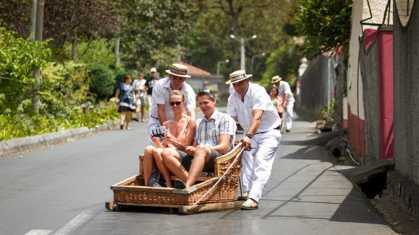 Turistas divertidos em passeio de cestos na Madeira
